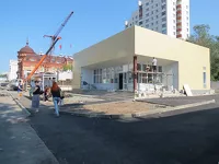 Остановка на фоне строящихся зданий. На тротуаре с трудом могут разойтись два человека