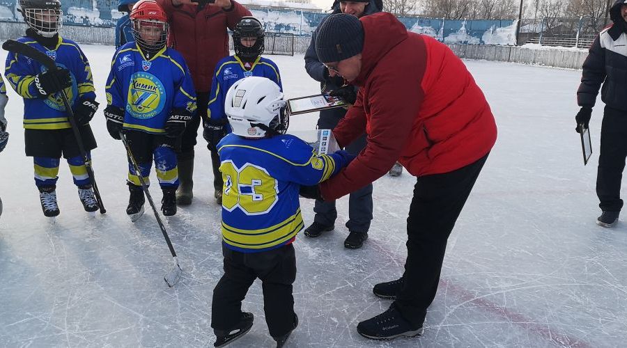 Андрей Худяев вручает подарок юному хоккеисту