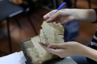 Исследователь держит в руках фрагмент рукописи