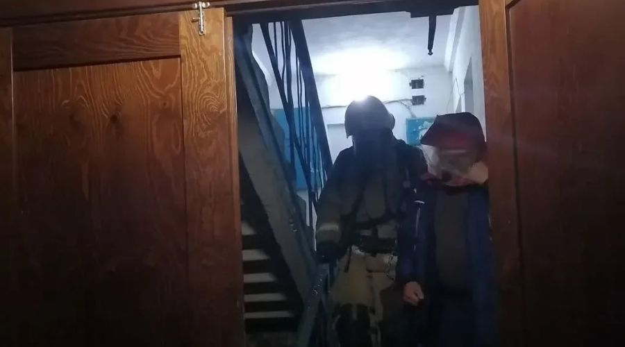 Пожарный эвакуирует жителя многоквартирного дома